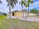 A lovely single-story home boasts a vibrant yellow facade, landscaped yard, and a brick driveway, framed by palm trees at 4826 San Ortebello Dr, Bradenton, FL 34208