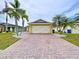 Home featuring a brick driveway, two-car garage, and tropical landscaping at 4826 San Ortebello Dr, Bradenton, FL 34208