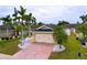 Charming home featuring a brick driveway, two-car garage, and tropical landscaping with palm trees at 4826 San Ortebello Dr, Bradenton, FL 34208