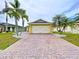A delightful single-story home features a yellow exterior, brick driveway, complemented by palm trees and a green lawn at 4826 San Ortebello Dr, Bradenton, FL 34208