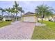 Charming single-story home in bright yellow with a brick driveway, palm trees and green lawn at 4826 San Ortebello Dr, Bradenton, FL 34208