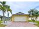 Charming home featuring a two-car garage, brick driveway, and picturesque palm tree landscaping at 4826 San Ortebello Dr, Bradenton, FL 34208