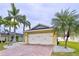Charming home featuring a two-car garage, brick driveway, and lovely landscaping with decorative stones and palm trees at 4826 San Ortebello Dr, Bradenton, FL 34208