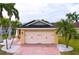 Charming home featuring a two-car garage, brick driveway, and lovely landscaping with decorative stones and palm trees at 4826 San Ortebello Dr, Bradenton, FL 34208