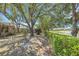 Large backyard with mature trees, a neatly trimmed privacy hedge, and pond views at 4926 72Nd E St, Bradenton, FL 34203