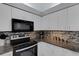 Well-equipped kitchen showcasing white cabinets, modern appliances, and sleek countertops with a stylish mosaic backsplash at 4926 72Nd E St, Bradenton, FL 34203
