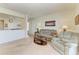 Open-concept living room with neutral carpeting, comfortable seating, and a view into the kitchen area at 5102 98Th E Ave, Parrish, FL 34219