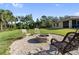 Outdoor fire pit with chairs on a gravel patio in a landscaped backyard, perfect for entertaining at 5955 Ferendina St, North Port, FL 34291