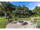 Backyard featuring a stone fire pit with multiple seating arrangements, set amongst mature palm trees at 5955 Ferendina St, North Port, FL 34291