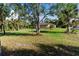 Expansive front yard with mature trees, a well-maintained lawn, and a charming home at 5955 Ferendina St, North Port, FL 34291