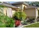Landscaped front yard of tan home with tropical plants, rock garden, and covered entryway at 5955 Ferendina St, North Port, FL 34291