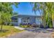Charming home's entrance featuring black awnings, a welcoming white door, and lush landscaping at 6013 Murdock Ave, Sarasota, FL 34231