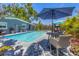 Relaxing pool area with an outdoor table set under a large patio umbrella at 6013 Murdock Ave, Sarasota, FL 34231