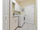 Laundry room featuring a washer, a dryer, white cabinets, and tile floors at 6110 Misty Oaks St, Sarasota, FL 34243