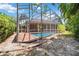 Backyard pool area with screened-in lanai and beautiful tropical trees at 6110 Misty Oaks St, Sarasota, FL 34243
