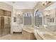 Bright bathroom features a soaking tub under large windows, double vanities, and a glass enclosed shower at 6520 38Th E Ln, Sarasota, FL 34243