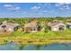 Back exterior view of a lakeside home with a well-manicured lawn and palm trees at 6520 38Th E Ln, Sarasota, FL 34243