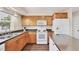Modern kitchen with wooden cabinets, white appliances, and laminate flooring at 6611 2Nd Ne Ave, Bradenton, FL 34208