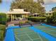 Shaded community gazebo with seating area next to shuffleboard courts with mature landscaping and blue sky backdrop at 6902 11Th W Ave, Bradenton, FL 34209