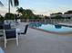 Community pool with lounge chairs, tables, umbrellas, and mature tropical landscaping at 6902 11Th W Ave, Bradenton, FL 34209
