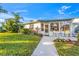 Charming home with lush landscaping, a sidewalk, and a welcoming front porch area at 7311 7Th W Ave # 7311, Bradenton, FL 34209