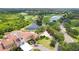 Aerial view of clubhouse with red tile roof, lush green lawn, and golf course with pond and trees at 8005 Royal Birkdale Cir, Lakewood Ranch, FL 34202