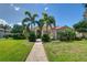 Beautiful home featuring lush landscaping, stately palm trees and a red tile roof on a sunny day at 8005 Royal Birkdale Cir, Lakewood Ranch, FL 34202