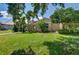 Well-manicured front yard with lush green grass, mature trees, and a glimpse of the charming home at 8005 Royal Birkdale Cir, Lakewood Ranch, FL 34202