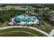 An aerial view showcasing a community pool area with slides, seating, and palm trees at 11713 Chevelon Ln, Parrish, FL 34219