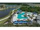 Aerial view of the community pool area with a waterslide, palm trees, lounge chairs, and blue canopies overlooking the lake at 11713 Chevelon Ln, Parrish, FL 34219