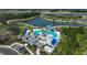 Aerial view of the community pool area with a waterslide, palm trees, lounge chairs, and blue canopies overlooking the lake at 11713 Chevelon Ln, Parrish, FL 34219