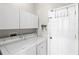 Laundry room with large capacity washer and dryer, white cabinets and access to side yard at 12014 Beeflower Dr, Lakewood Ranch, FL 34202