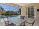 Covered patio with dining table offering views of a screened-in pool and lush tropical landscaping at 12014 Beeflower Dr, Lakewood Ranch, FL 34202