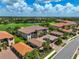 Aerial view of a community with tiled roof homes, lush landscaping, and golf course and water views at 12720 Sorrento Way # 103, Bradenton, FL 34211