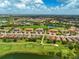 Expansive aerial view of a golf community with lakes, tiled roof homes, and lush fairways under a partly cloudy sky at 12720 Sorrento Way # 103, Bradenton, FL 34211