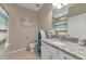 Well-lit bathroom featuring a granite countertop, blue accents, and tub with shower at 12720 Sorrento Way # 103, Bradenton, FL 34211