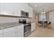 Contemporary kitchen featuring white cabinets, granite countertops, stainless steel oven, and a view into the dining area at 12720 Sorrento Way # 103, Bradenton, FL 34211