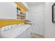 Laundry room with white washer and dryer, white cabinets, and a bright yellow accent wall at 13786 Vancanza Dr, Venice, FL 34293