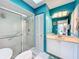 Stylish bathroom with a walk-in shower, white cabinets, bright blue paint, and a skylight at 1447 Gleneagles Dr, Venice, FL 34292