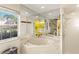 Bright bathroom featuring a tub, shower, and a window with views of the lush exterior at 1447 Gleneagles Dr, Venice, FL 34292