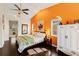 Bright bedroom featuring a ceiling fan, hardwood floors, and an orange accent wall at 1447 Gleneagles Dr, Venice, FL 34292