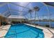 Sparkling screened pool boasts a tranquil lake view, comfortable lounge chairs, and lush landscaping at 1447 Gleneagles Dr, Venice, FL 34292