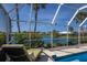 Screened-in pool with lake view, lounge chair, and tiled deck offers serene outdoor living at 1447 Gleneagles Dr, Venice, FL 34292