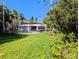 Backyard featuring a beautiful swimming pool, lush green lawn, and plenty of tropical plants at 173 Bath Club N Blvd, North Redington Beach, FL 33708