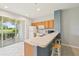 Well-lit kitchen with breakfast bar, bright cabinets, stainless appliances, and sliding glass doors to patio at 2353 Rosewood Ln, North Port, FL 34289