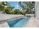 Backyard pool with sun loungers and a water feature, surrounded by lush greenery and privacy fence at 2596 Floyd St, Sarasota, FL 34239
