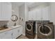 Modern laundry room with a stylish backsplash, white cabinets, and front-load washer and dryer at 2806 Starwood Ct, Lakewood Ranch, FL 34211