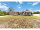 A tan single-story home with a two-car garage and solar panels is accented by bright-white trim and fresh landscaping at 3453 Dryden St, North Port, FL 34288
