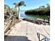 Landscaped backyard area featuring tiled patio, bench seating, palm trees, and water access for relaxation at 36 N Starboard Dr, Venice, FL 34285