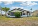 Rear exterior view of a home with large screened windows, green shrubbery, and a bright blue sky above at 4265 Hoffman Ave, Spring Hill, FL 34606